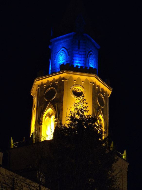 A tower illuminated by blue and yellow